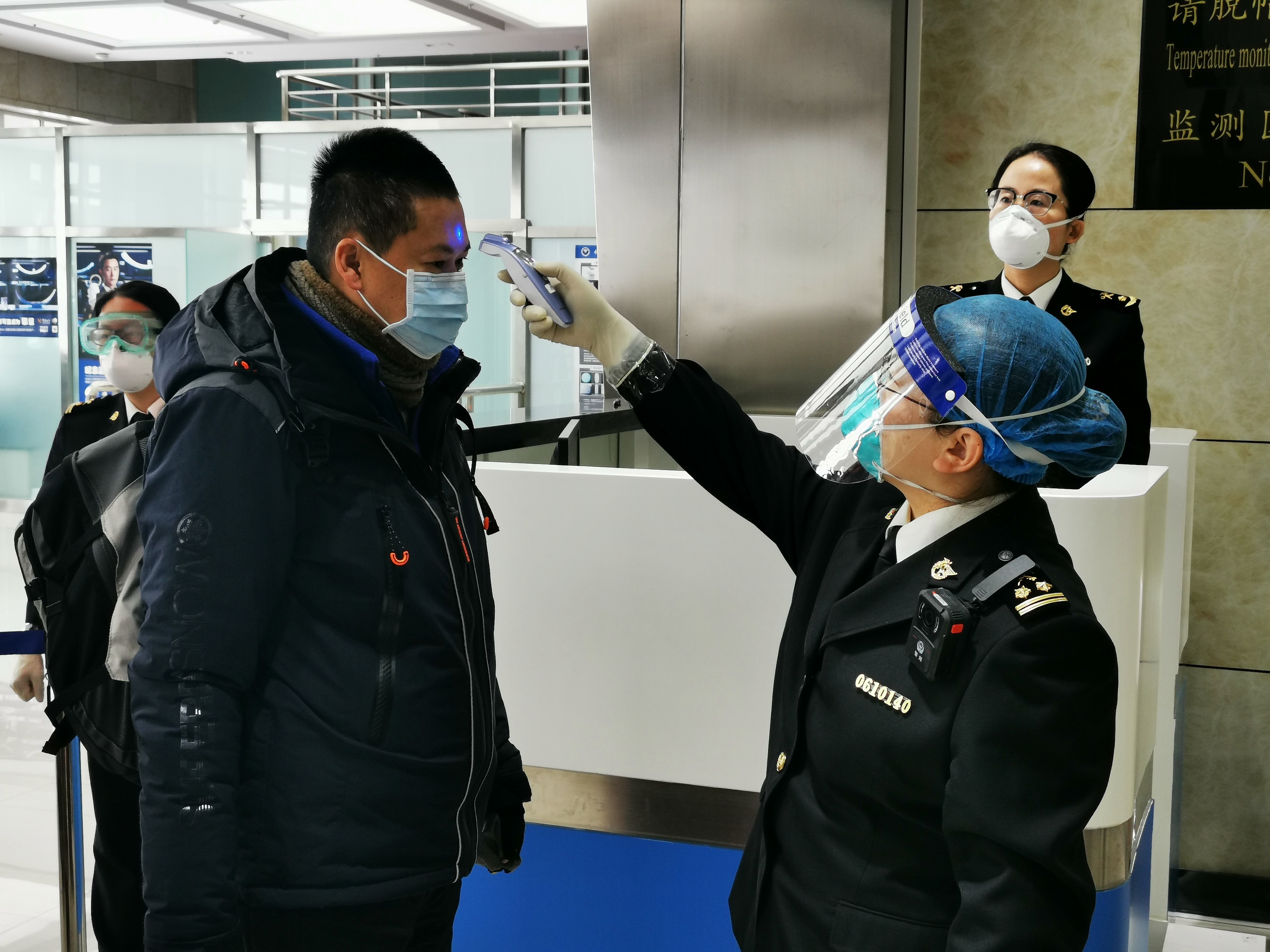 图为:海关关员对旅客开展体温检测.jpg